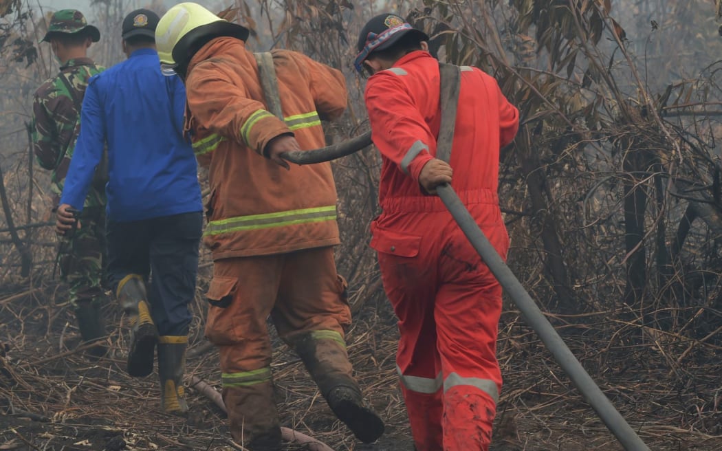 Indonesian firemen pull a hose as they put out a fire in Kampar, Riau province.