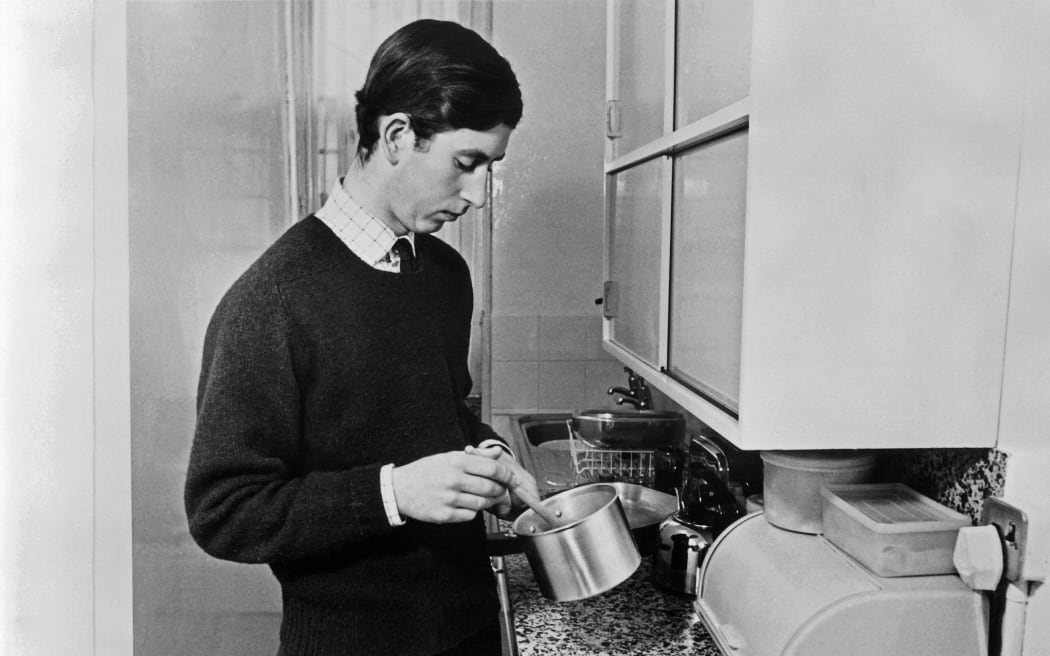 Picture taken on February 8, 1971 at Cambridge showing Charles, Prince of Wales, preparing a meal in the kitchen of his apartement at the university of the city. (Photo by CENTRAL PRESS / AFP)