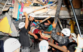 Rescue workers work to pull out people trapped in a building in Manta.