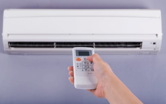 Hand holding remote control directed on the air conditioner