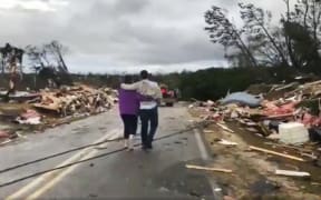 People walk amid debris in Lee County, Ala., after what appeared to be a tornado struck in the area Sunday, March 3, 2019.