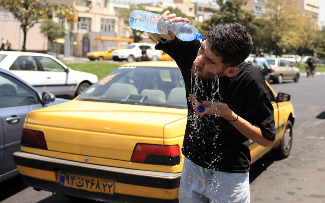 An Iranian taxi driver cools down by splashing water on his face on a street amid soaring temperatures in Tehran on July 22, 2025. Iranian authorities have urged residents to limit water consumption as the country grapples with severe shortages amid an ongoing heatwave, local media reported. On July 19, the national meteorological service said Iran was experiencing its hottest week of the year so far, with temperatures exceeding 50 degrees Celsius (122 Fahrenheit) in some areas. (Photo by AFP)