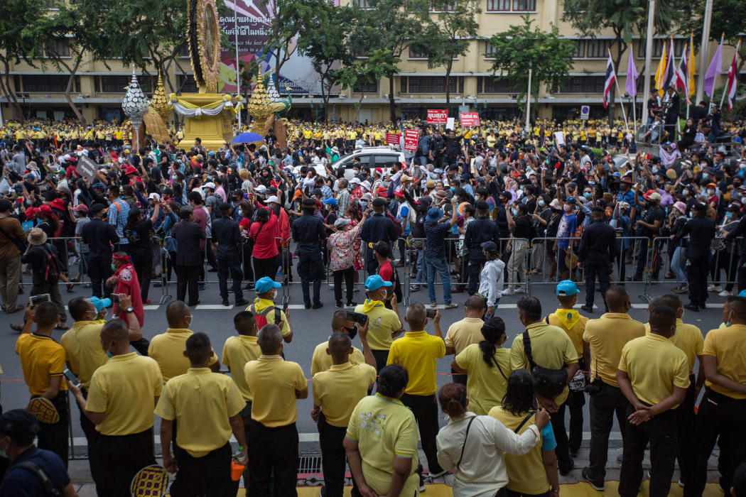 Pro-democracy protesters walk towards Government House as people dressed in pro-monarchy yellow t-shirts look on, Bangkok, 14 October 2020.