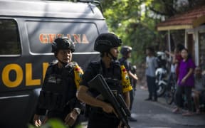Indonesian police officers patrol outside a church following a suicide bomb in Surabaya.