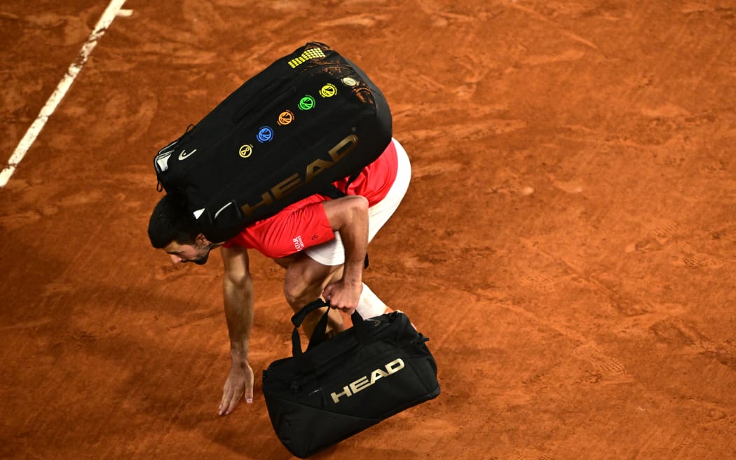 Serbia's Novak Djokovic touches the clay court as he leaves after losing his men's singles semi-final match against Italy's Jannik Sinner on day 13 of the French Open tennis tournament on Court Philippe-Chatrier at the Roland-Garros Complex in Paris on June 6, 2025. (Photo by JULIEN DE ROSA / AFP)