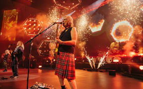 Still from Spinal Tap II: The End Continues showing Nigel Tufnell (Christopher Guest) on stage wearing a kilt.