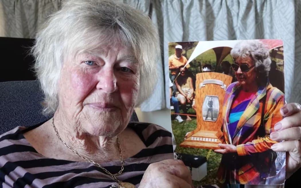 Cherry Daly with a photo of her mother Gwen Daly and the Mick Griffin Memorial Trophy, named in honour of her axeman grandfather. Photo: RNZ/Peter de Graaf