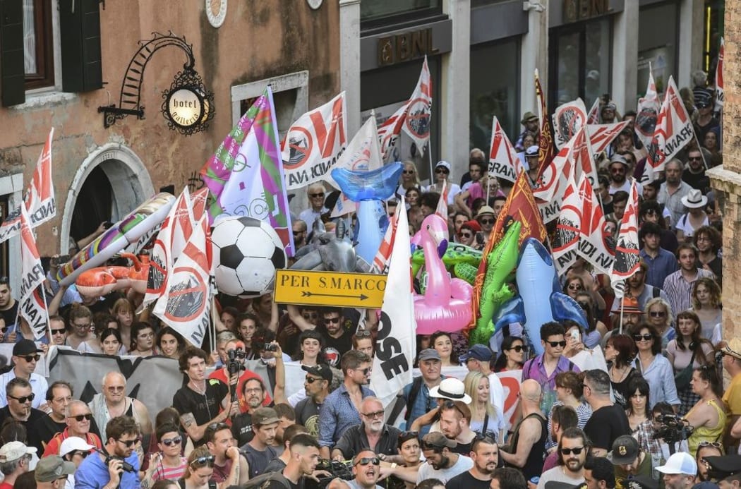 People hold flags and banners during a demonstration called by the No Great Ships movement against big cruise ships sailing into the Venice lagoon on June 8, 2019, in Venice.