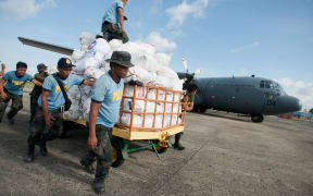 Philippine police help load an RNZAF C-130 Hercules with food for typhoon survivors.