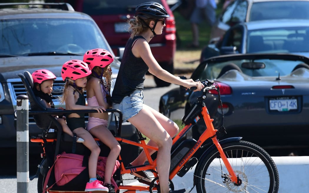 A woman and three children go on a cooling bike ride on a scorching hot day, in Vancouver, British Columbia, June 29, 2021.