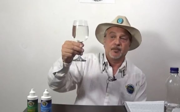 Mark Grenon holds a glass containing chlorine dioxide bleach and water, which he calls Miracle Mineral Solution