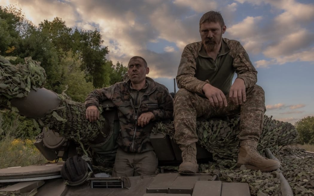 Ukrainian tank crew take a break while operating a Soviet-made T-72 tank in the Sumy region, near the border with Russia, on August 12, 2024, amid the Russian invasion of Ukraine. Ukraine launched a surprise offensive into the Russian border region of Kursk on August 6, 2024, capturing over two dozen towns and villages in the most significant cross-border attack on Russian soil since World War II. Ukraine's military chief Oleksandr Syrsky told President Volodymyr Zelensky in a video posted on August 12, 2024 that his troops now control about 1,000 square kilometres of Russian territory and are continuing "offensive operations". (Photo by Roman PILIPEY / AFP)