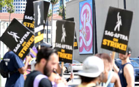 Members of the Writers Guild of America and the Screen Actors Guild walk a picket line outside of Warner Bros Studio in Burbank, California, on July 26, 2023. Tens of thousands of Hollywood actors went on strike at midnight July 14, 2023, effectively bringing the giant movie and television business to a halt as they join writers in the first industry-wide walkout for 63 years. (Photo by VALERIE MACON / AFP)