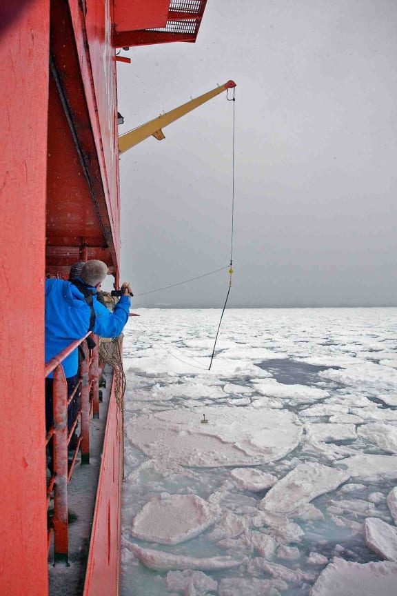 A buoy to measure waves in the Southern Ocean is lowered on to sea ice from the research vessel Aurora Australis.