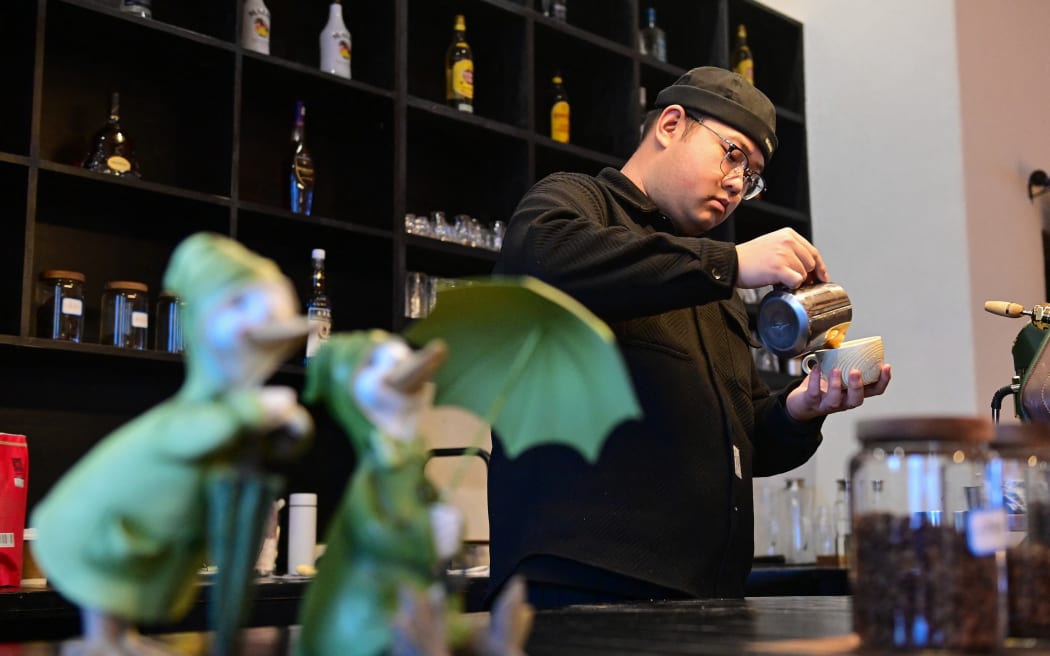 (231223) -- TALAT, Dec. 23, 2023 (Xinhua) -- A barista makes coffee at a cafe in Talat Village in Koktokay in Fuyun County, northwest China's Xinjiang Uygur Autonomous Region, Dec. 22, 2023.
 Located near the source of the Ertix River, Talat Village is dubbed as 