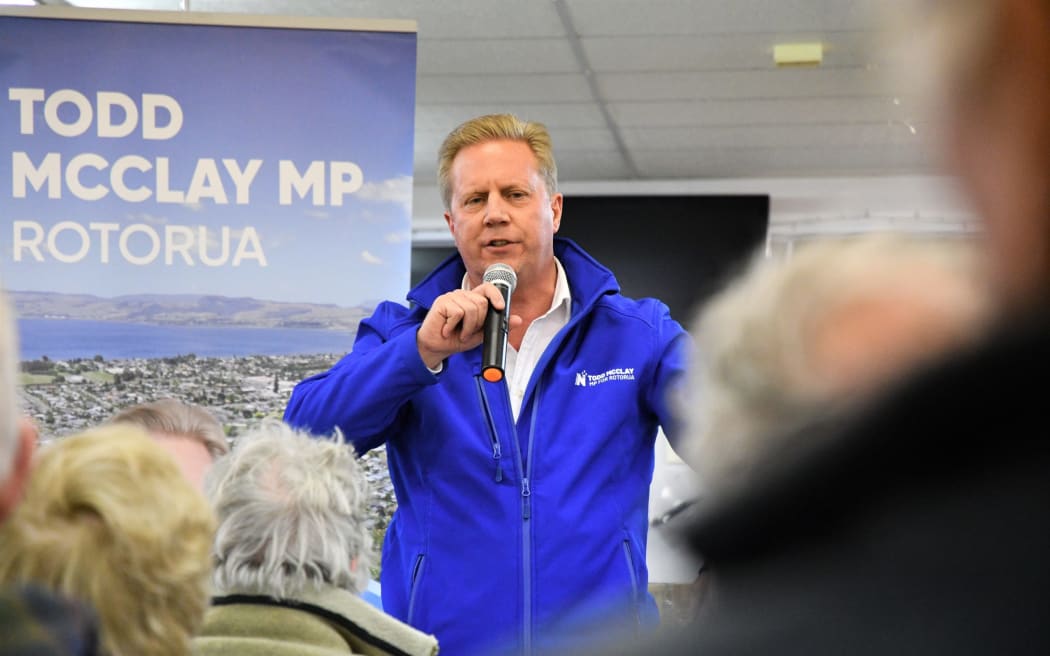 National Party Rotorua MP Todd McClay speaking into a microphone at a meeting.
