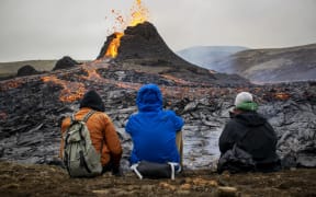 Sunday hikers look at the lava flowing from the erupting Fagradalsfjall volcano some 40 km west of the Icelandic capital Reykjavik.