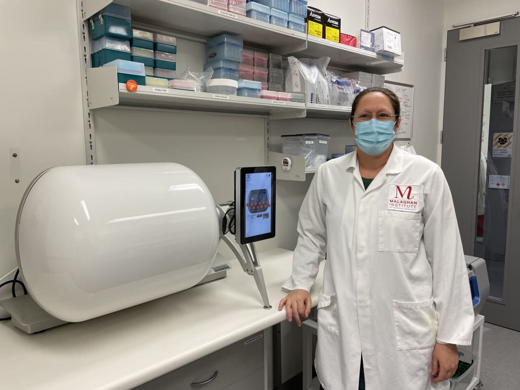 Dr. Rachel Perret beside the new cocoon equipment that will make CAR T-cells more efficiently.