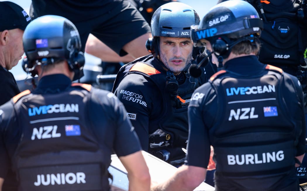 Blair Tuke, co-CEO and wing trimmer of New Zealand SailGP Team, speaks with crew members.