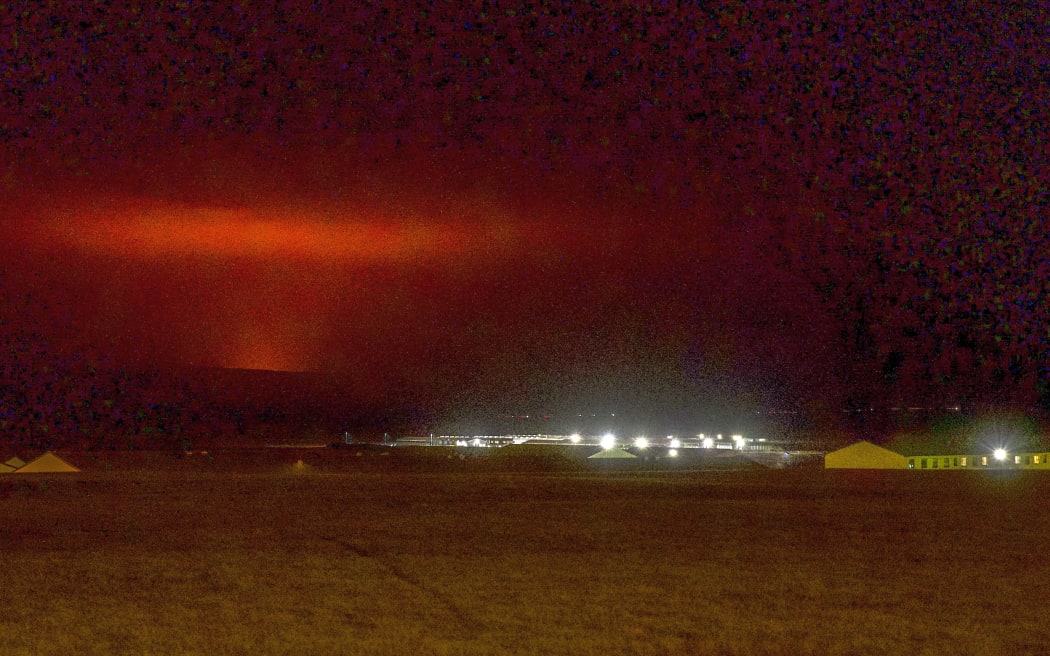 The red shimmer from magma is seen coming out from the erupting Fagradalsfjall volcano behind the town of Keflavik, in Iceland.