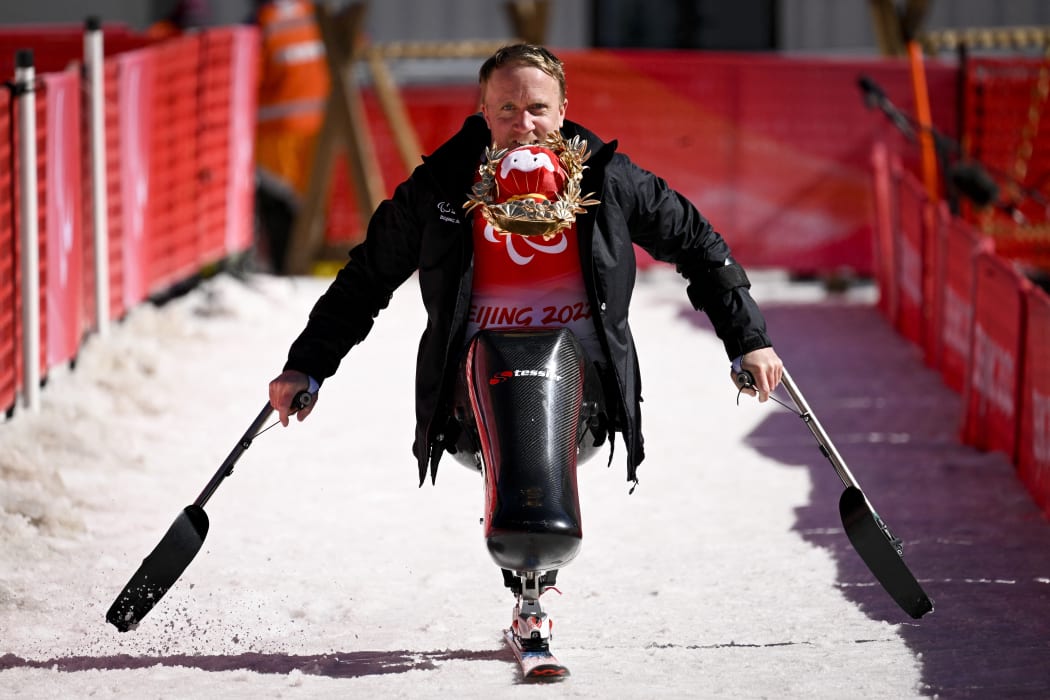 Corey Peters of New Zealand holding Shuey Rhon Rhon, mascot of the Beijing 2022 Winter Paralympic Games in his mouth, celebrates after winning the men's downhill sitting event at the Yanqing National Alpine Skiing Centre on March 5, 2022.