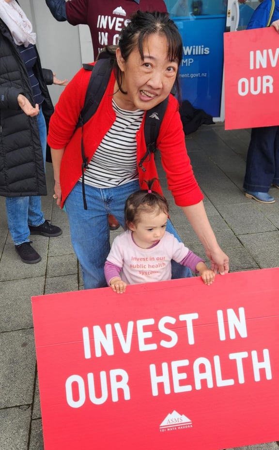 Wellington Regional Hospital gastroenterologist Amanda Chen - pictured here with two-year-old daughter Roisin picketing outside Finance Minister Nicola Willis' office - says doctors would rather be treating their patients than going on strike.