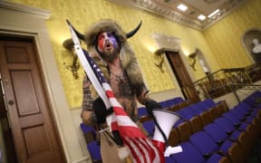 Jacob Anthony Chansley is alleged to be the man seen wearing horns and a fur hat in photographs, including this from inside the Senate chamber.