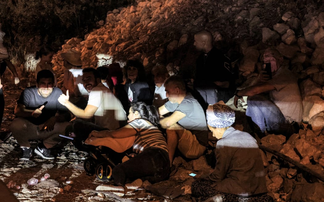 People take cover under a bridge along a highway between Kafr Qara and Baqa al-Gharbiya in northern Israel on October 1, 2024. Air raid sirens sounded in central Israel on October 1, the military said, a day after the army launched ground operations into southern Lebanon targeting Hezbollah positions. 