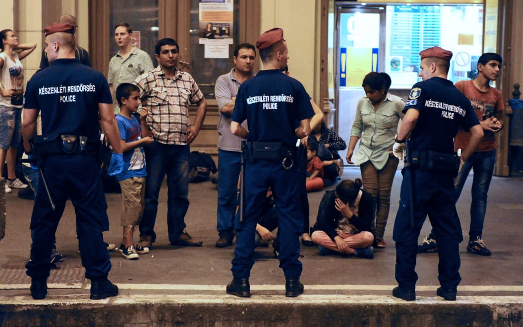 Migrants wait on a platform of the Eastern (Keleti) railway station of Budapest behind of a line of the local police on August 31, 2015, as the last train left in direction of Austria and Germany.