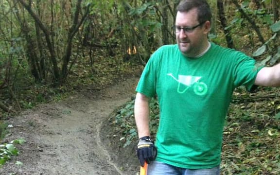 Man stands on dirt track with spade