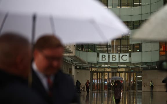 People shelter from the rain outside the entrance to the BBC in London on 10 November, 2025.