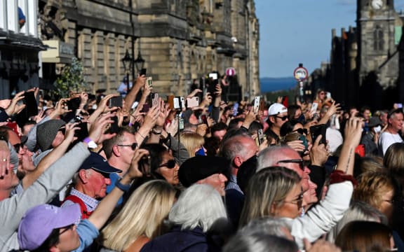 Members of the public wait to see the hearse carrying the coffin of Queen Elizabeth II, leave from from St Giles' Cathedral in Edinburgh on September 13, 2022, headed for Edinburgh airport. - Charles III on Tuesday made his maiden visit to Northern Ireland as king, as he tours all four nations of the United Kingdom before next week's state funeral of his mother Queen Elizabeth II. The casket will be flown on Tuesday evening to London, where huge crowds are expected to pay their respects as she lies in state from Wednesday evening until her funeral on Monday morning. (Photo by Oli SCARFF / AFP)