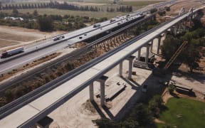 In this aerial image taken on August 26, 2021 vehicles drive past farmland and part of the California High Speed Rail Authority San Joaquin River viaduct construction project alongside US Highway 99 through the Central Valley between Madera County and Fresno County, California.