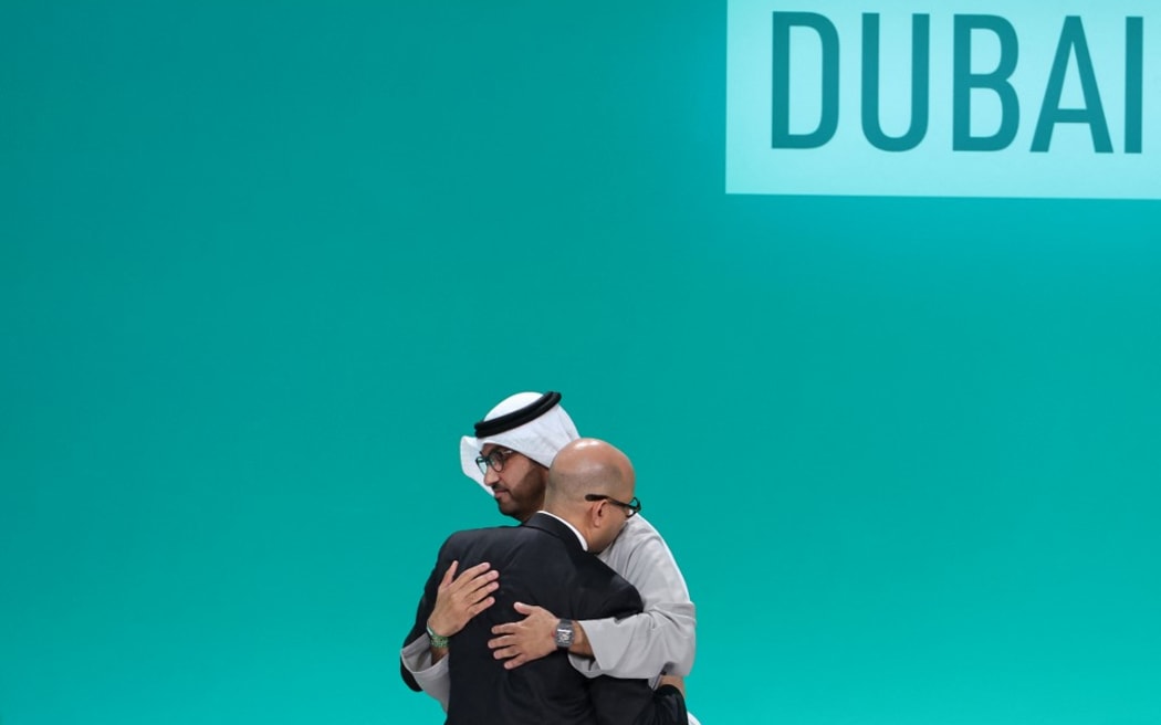 COP28 president Sultan Ahmed Al Jaber (R) and United Nations Framework Convention on Climate Change (UNFCCC) Executive Secretary Simon Stiell embrace at a plenary session during the United Nations climate summit in Dubai on December 13, 2023. Nations adopted the first ever UN climate deal that calls for the world to transition away from fossil fuels. "We have the basis to make transformational change happen," COP28 president Sultan Al Jaber said at the UN climate summit in Dubai before the deal was adopted by consensus, prompting delegates to rise and applaud. (Photo by Giuseppe CACACE / AFP)
