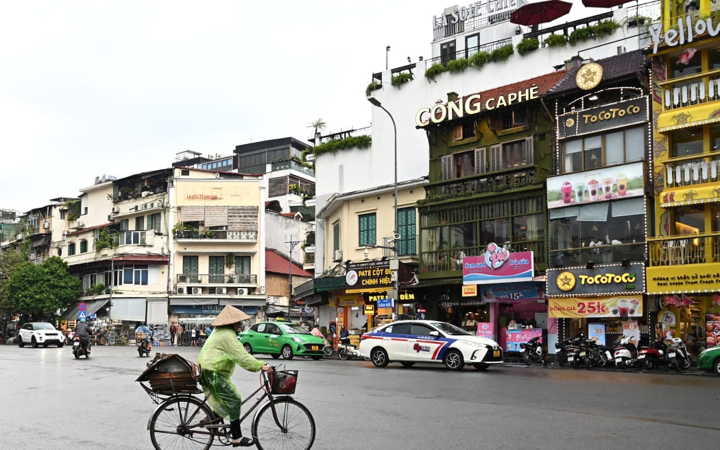 A woman rides a bicycle on the street in Hanoi on September 25, 2023 (Photo by Nhac NGUYEN / AFP)