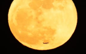 An airplane passes across a full moon in the night sky over Tokyo on Jan. 2, 2018. The phenomenon of "supermoon'' happened when the orb was the closest point to the earth and looked larger than usual.