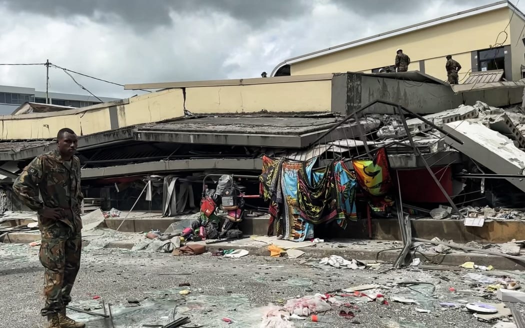 This screengrab taken from handout video footage posted on the Facebook account of Michael Thompson on December 17, 2024 shows a member of security inspecting a collapsed building in Vanuatu's capital Port Vila after a powerful earthquake hit the Pacific island. - The 7.3-magnitude quake struck on December 17 at a depth of 57 kilometres (35 miles), some 30 kilometres off the coast of Efate, Vanuatu's main island, at 12:47 pm (0147 GMT), according to the US Geological Survey. (Photo by MICHAEL THOMPSON / Facebook account of Michael Thompson / AFP) / NO USE AFTER JANUARY 16, 2025 05:59:55 GMT - RESTRICTED TO EDITORIAL USE – MANDATORY CREDIT «AFP PHOTO / FACEBOOK / MICHAEL THOMPSON» - NO MARKETING NO ADVERTISING CAMPAIGNS – DISTRIBUTED AS A SERVICE TO CLIENTS [- NO ARCHIVE ]
