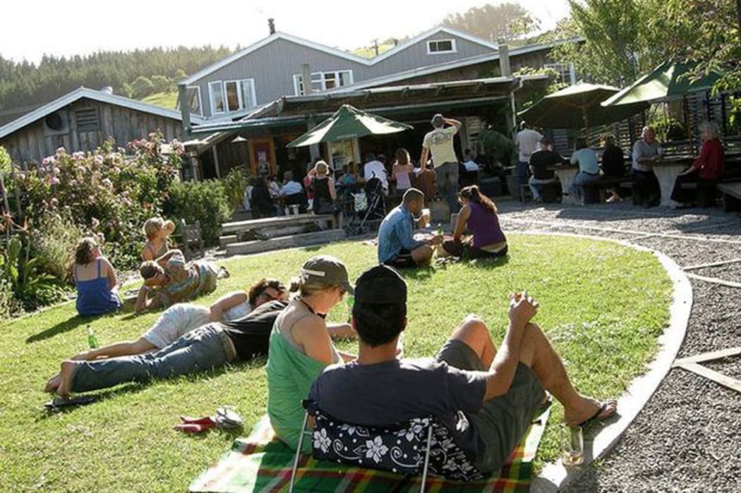 The Leigh Sawmill Cafe front lawn with people sitting in the sun.