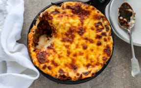 A round dish of lamb lasagne covered with a baked cheese topping.