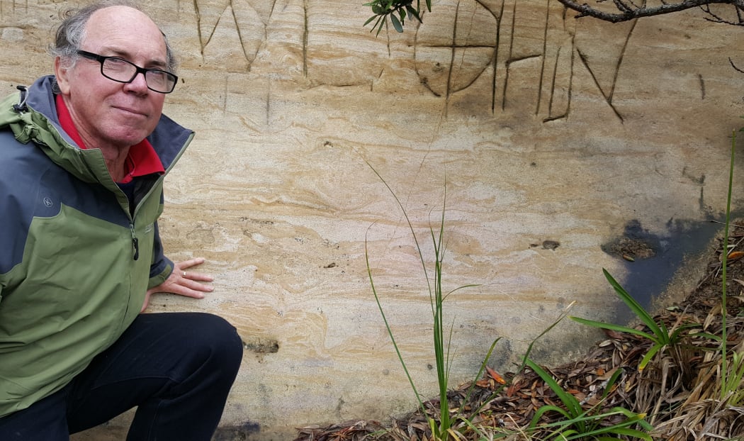 Bruce Hayward next to a cross-section of a moa footprint on a Muriwai road cutting.