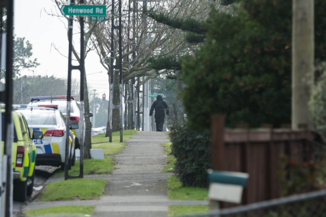 A man wearing protective gear heads towards the property at the centre of the cordon.