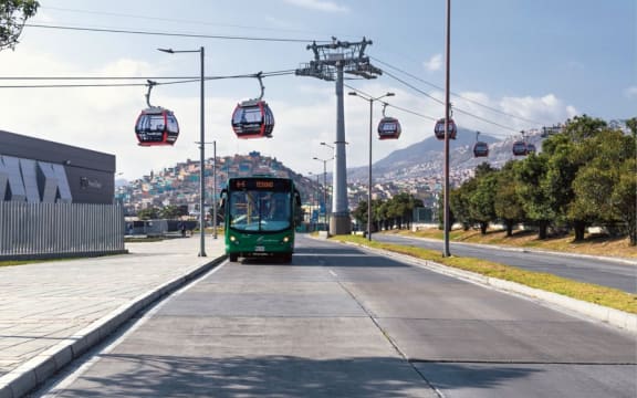 An image of a cable car crossing a road above a bus.