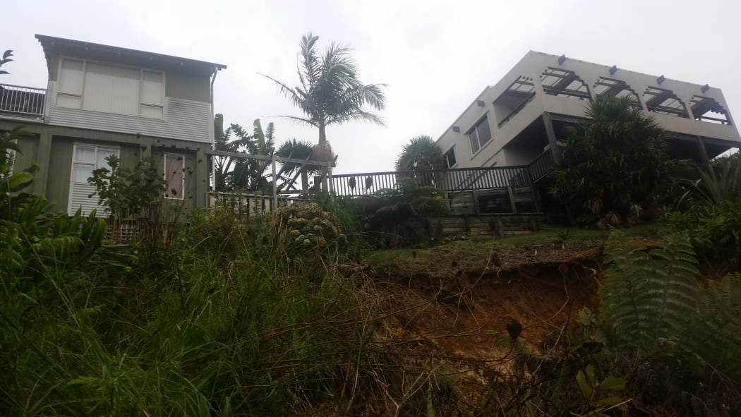 Michael Robertson's house (right) has been condemned until further notice because the soft ground underneath could mean his house goes down bank in another downpour.