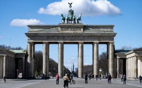Passers-by stand on Pariser Platz in front of the Brandenburg Gate, 20 March.