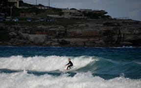 A surfer rides a wave at Bondi Beach.