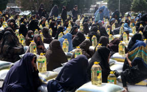 Women receive food aid distributed by a charity foundation during the Islamic holy month of Ramadan in Herat on 11 April, 2023.