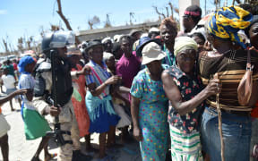 A Haitian policeman tries to keep Hurricane Matthew victims in order as they wait to receive food from the UN's World Food Programme in Roche-a-Bateaux, in Les Cayes.