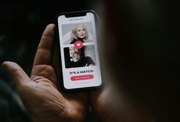 A pair of hands hold a phone which shows a "match" on a dating app.