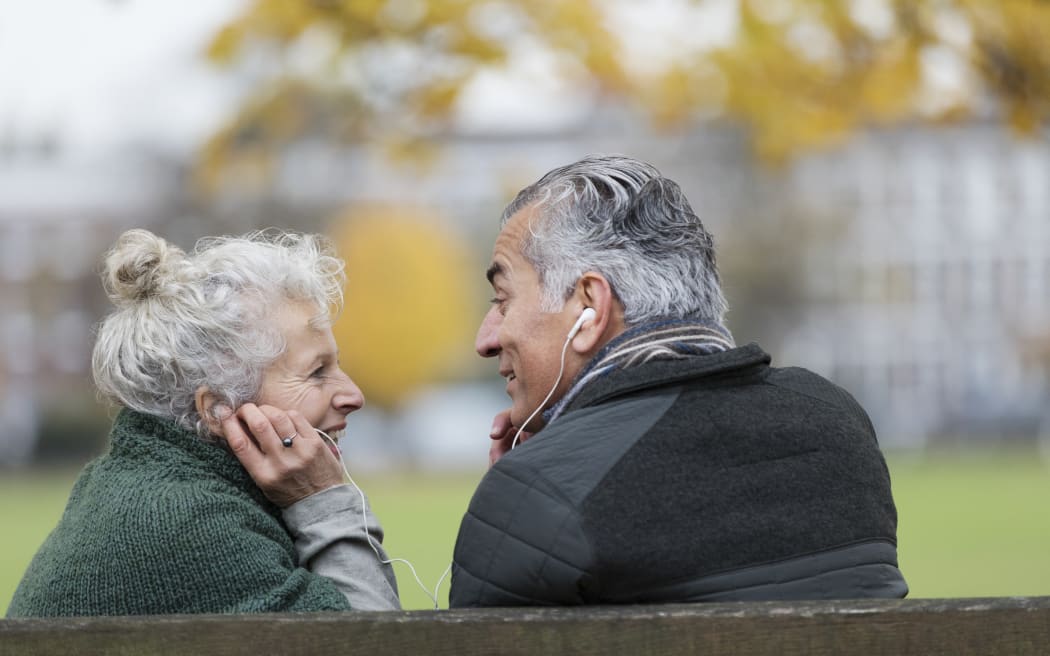 Happy senior couple sharing headphones, listening to music in park. (Photo by Tom Merton/CAIA IMAGE/CAIA IMAGE / NEW / Science Photo Library via AFP)