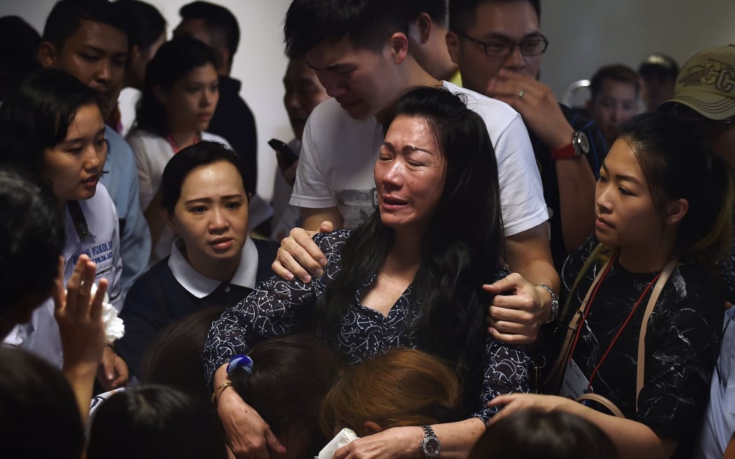 Family members of passengers onboard missing Malaysian air carrier AirAsia flight QZ8501 react after watching news reports showing an unidentified body floating in the Java sea.